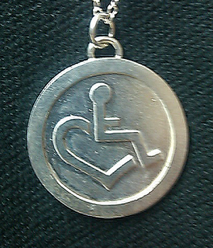 Sterling Silver Coin Pendant Necklace. The sterling silver coin pendant on this necklace features an embossed representation of our trademarked International Symbol of Acceptance (Wheelchair Heart). Item is individually handcrafted and will last forever.